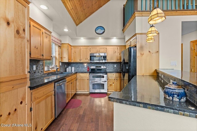 kitchen with decorative light fixtures, dark wood-type flooring, stainless steel appliances, sink, and lofted ceiling