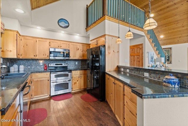 kitchen featuring dark wood-type flooring, stainless steel appliances, sink, decorative backsplash, and a high ceiling