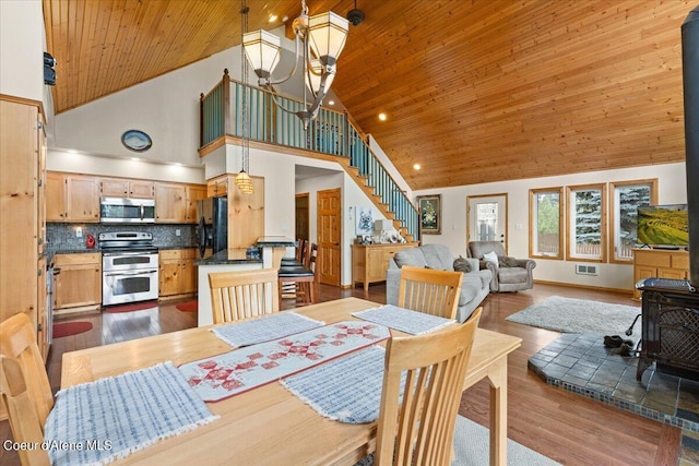 dining area featuring a wood stove, dark hardwood / wood-style floors, high vaulted ceiling, and a notable chandelier