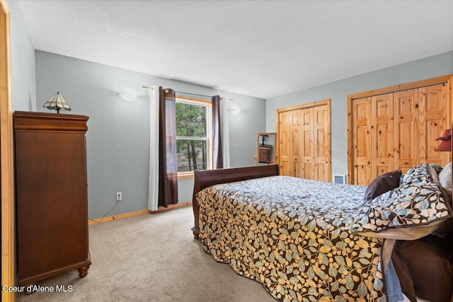 bedroom featuring a textured ceiling, two closets, and carpet floors