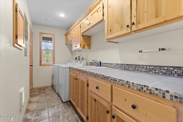 clothes washing area featuring washer and dryer, cabinets, and sink