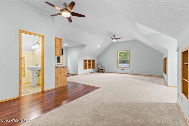 additional living space featuring a textured ceiling, light hardwood / wood-style flooring, ceiling fan, and vaulted ceiling