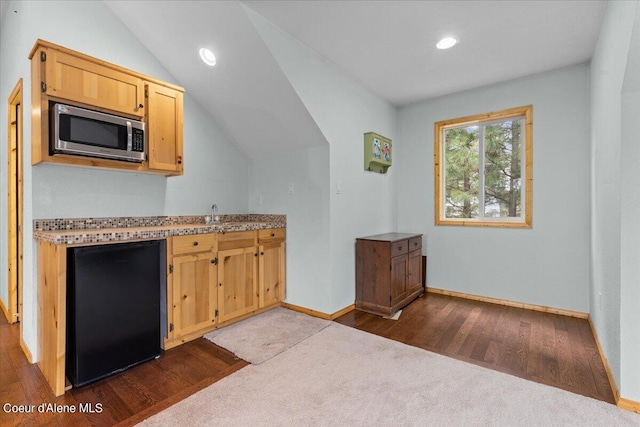 kitchen featuring black refrigerator, dark hardwood / wood-style floors, and vaulted ceiling