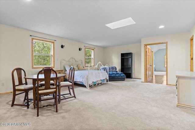 carpeted bedroom featuring a skylight and connected bathroom