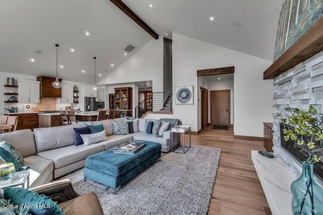 living room with light hardwood / wood-style flooring, beamed ceiling, and high vaulted ceiling