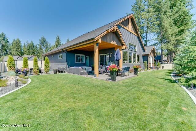 rear view of property with an outdoor living space, a yard, and a patio