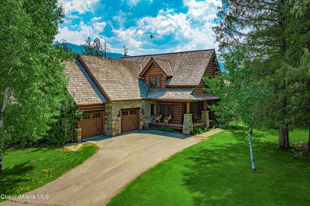 view of front facade featuring driveway, a garage, stone siding, and a front lawn