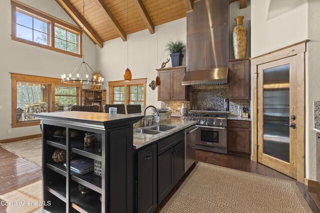 kitchen with stainless steel appliances, backsplash, a sink, extractor fan, and a kitchen island with sink