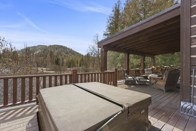 wooden deck featuring a wooded view and a mountain view