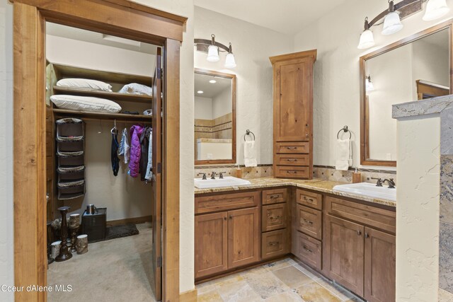 bathroom with double vanity, a sink, and a walk in closet