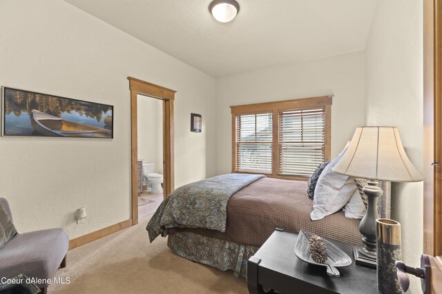 carpeted bedroom featuring baseboards and ensuite bathroom
