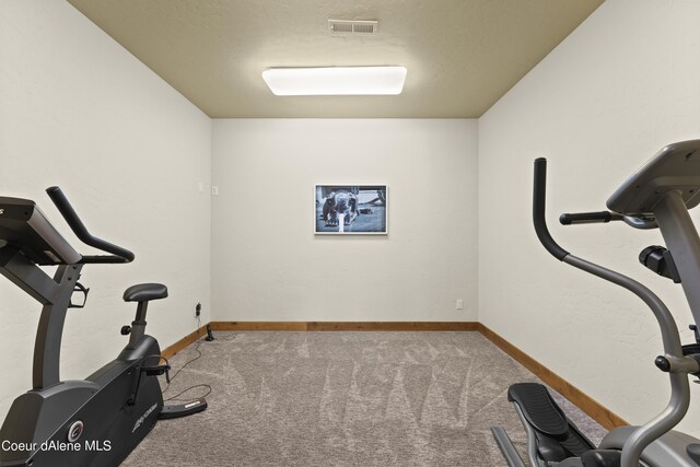 exercise area featuring baseboards, carpet floors, a textured ceiling, and visible vents
