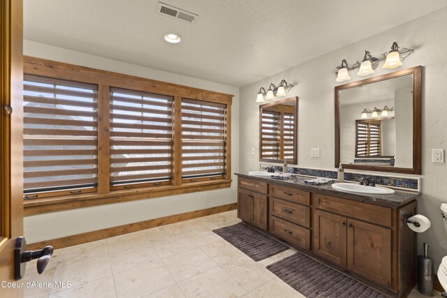 full bathroom featuring double vanity, a sink, baseboards, and visible vents