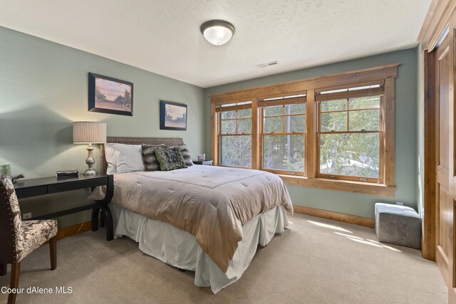 bedroom with baseboards, a textured ceiling, visible vents, and carpet