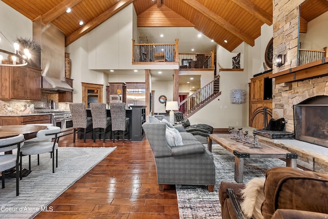 living area with dark wood-style floors, high vaulted ceiling, wooden ceiling, and stairs