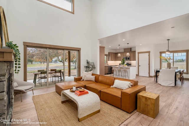 living room with light wood-type flooring, a fireplace, and a towering ceiling