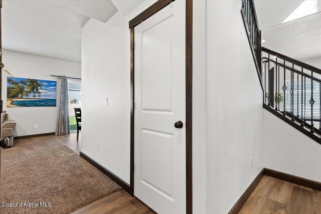 hallway with a textured ceiling and wood-type flooring