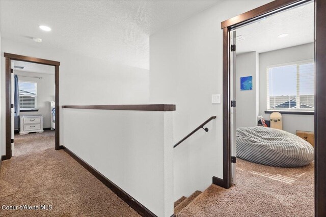 hallway with a textured ceiling and carpet flooring