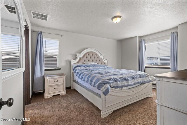 bedroom with a textured ceiling and dark colored carpet