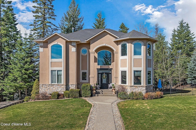 view of front facade with stone siding, a front yard, stucco siding, and fence