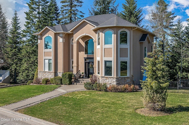view of front of home with stone siding, fence, a front yard, and stucco siding