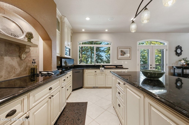 kitchen with stainless steel microwave, dark stone countertops, black electric stovetop, light tile patterned flooring, and dishwashing machine