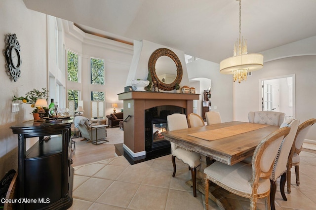 dining space with light tile patterned flooring, arched walkways, a chandelier, and a multi sided fireplace