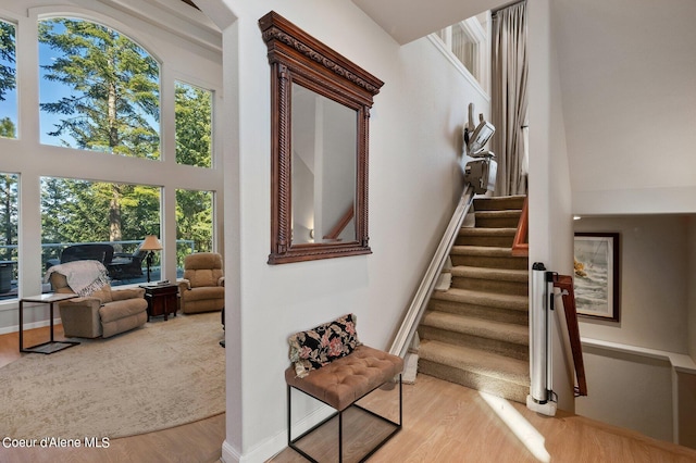 stairs with baseboards, wood finished floors, and a towering ceiling