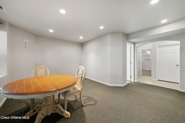carpeted dining area with arched walkways, visible vents, baseboards, and recessed lighting