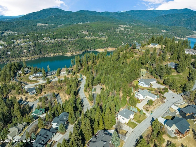 birds eye view of property featuring a water and mountain view and a wooded view