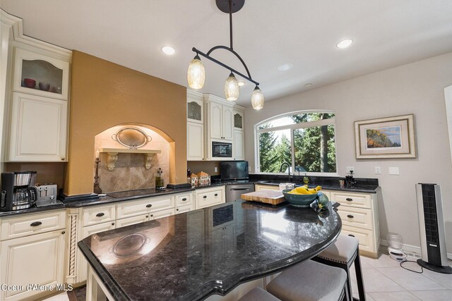kitchen with a breakfast bar area, light tile patterned floors, a kitchen island, black appliances, and glass insert cabinets