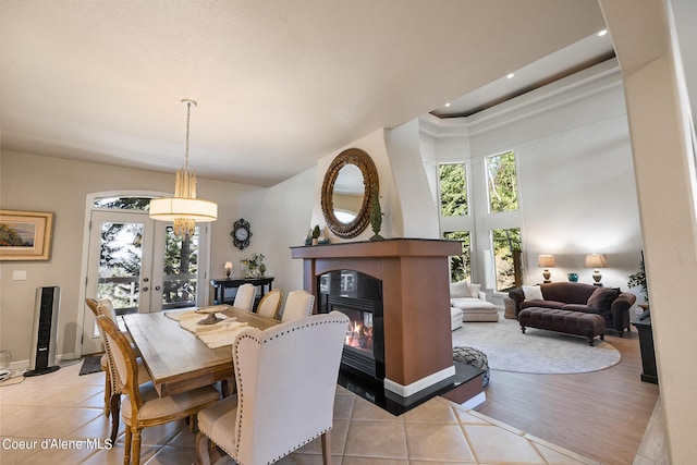 dining room featuring light tile patterned flooring, a high ceiling, a tiled fireplace, and french doors