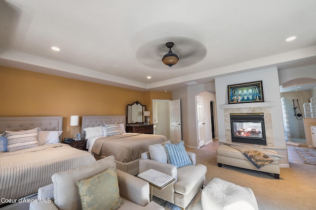 bedroom featuring carpet flooring, arched walkways, a fireplace, and recessed lighting