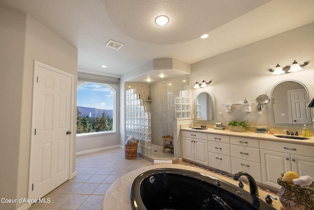 bathroom featuring a textured ceiling, tile patterned floors, a sink, double vanity, and a walk in shower