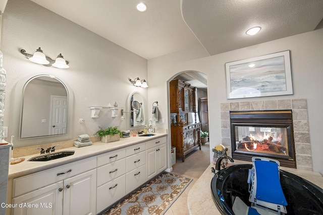 full bathroom with double vanity, a fireplace, tile patterned flooring, and a sink