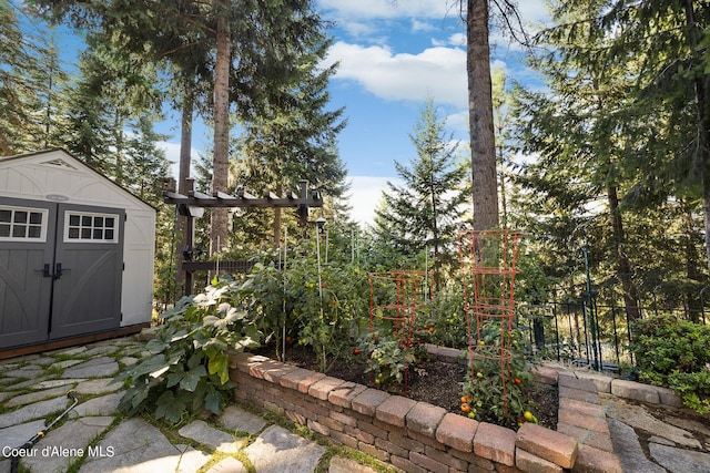 view of yard with an outdoor structure, a vegetable garden, a storage unit, and fence