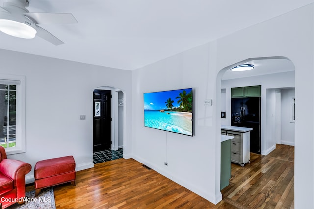 living room featuring ceiling fan and dark hardwood / wood-style floors