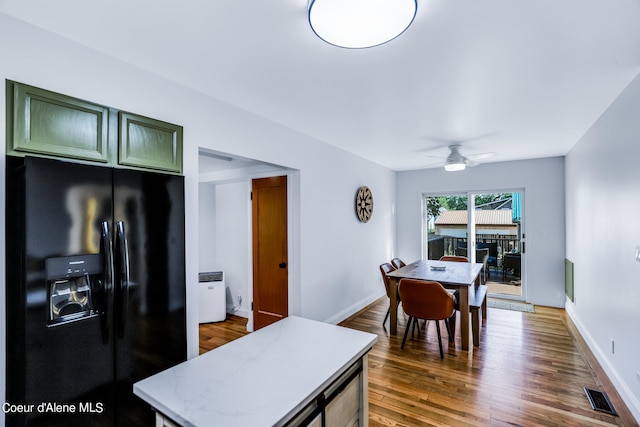 kitchen with green cabinets, black fridge with ice dispenser, dark hardwood / wood-style floors, and ceiling fan