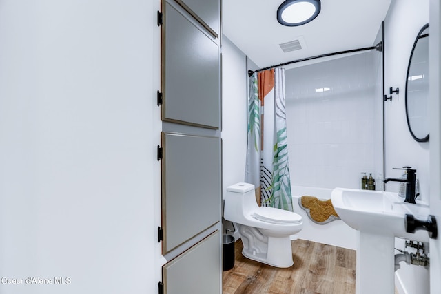 bathroom featuring shower / bath combo with shower curtain, hardwood / wood-style flooring, and toilet