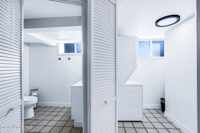 bathroom with toilet, tile patterned floors, and stacked washing maching and dryer