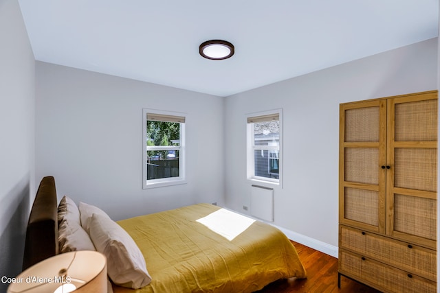 bedroom featuring heating unit and dark hardwood / wood-style flooring