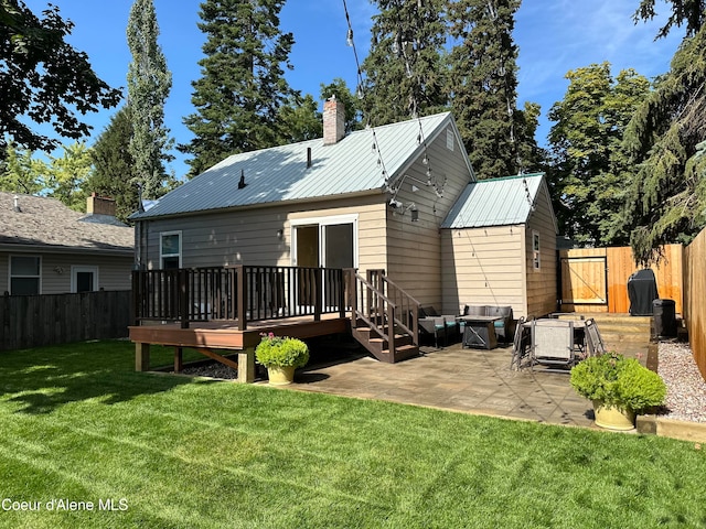 back of house with a deck, a lawn, and a patio area