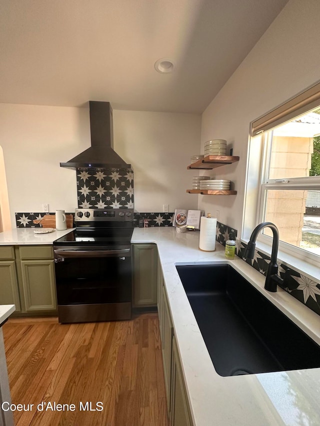 kitchen with wall chimney exhaust hood, light hardwood / wood-style flooring, stainless steel electric stove, and sink