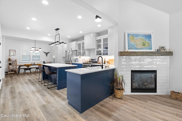 kitchen featuring white cabinets, a fireplace, light hardwood / wood-style floors, kitchen peninsula, and a kitchen breakfast bar