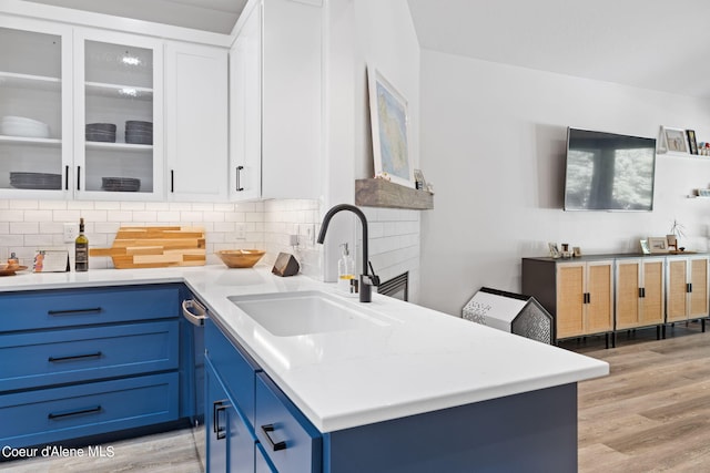 kitchen with blue cabinetry, sink, white cabinetry, and light hardwood / wood-style floors