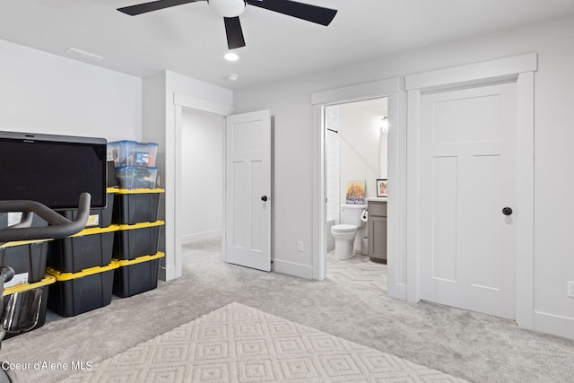 bedroom featuring light colored carpet, ceiling fan, and connected bathroom