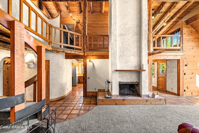 living room with a fireplace, wood ceiling, lofted ceiling with beams, and wooden walls