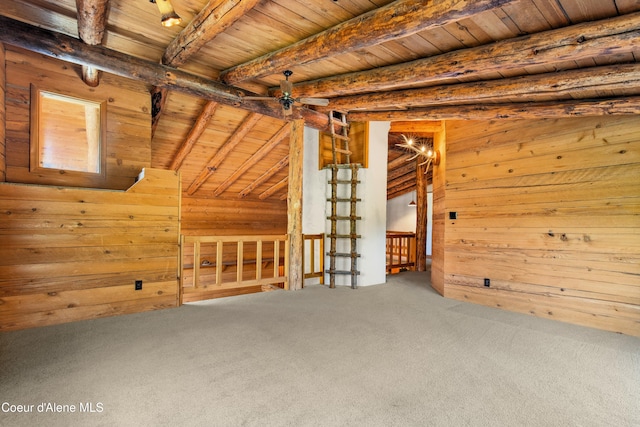 interior space featuring beam ceiling, wood walls, wooden ceiling, and carpet