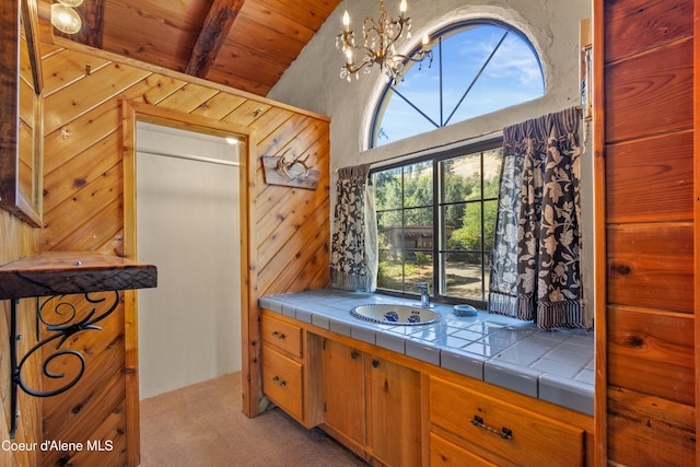 kitchen featuring wood ceiling, beam ceiling, a chandelier, tile countertops, and light carpet