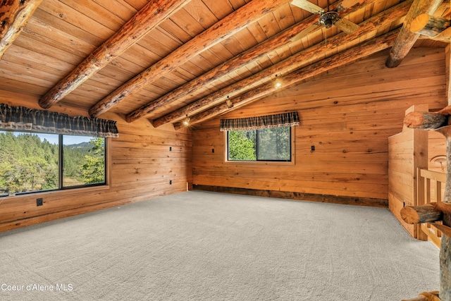 empty room with wood walls, wood ceiling, vaulted ceiling with beams, and carpet